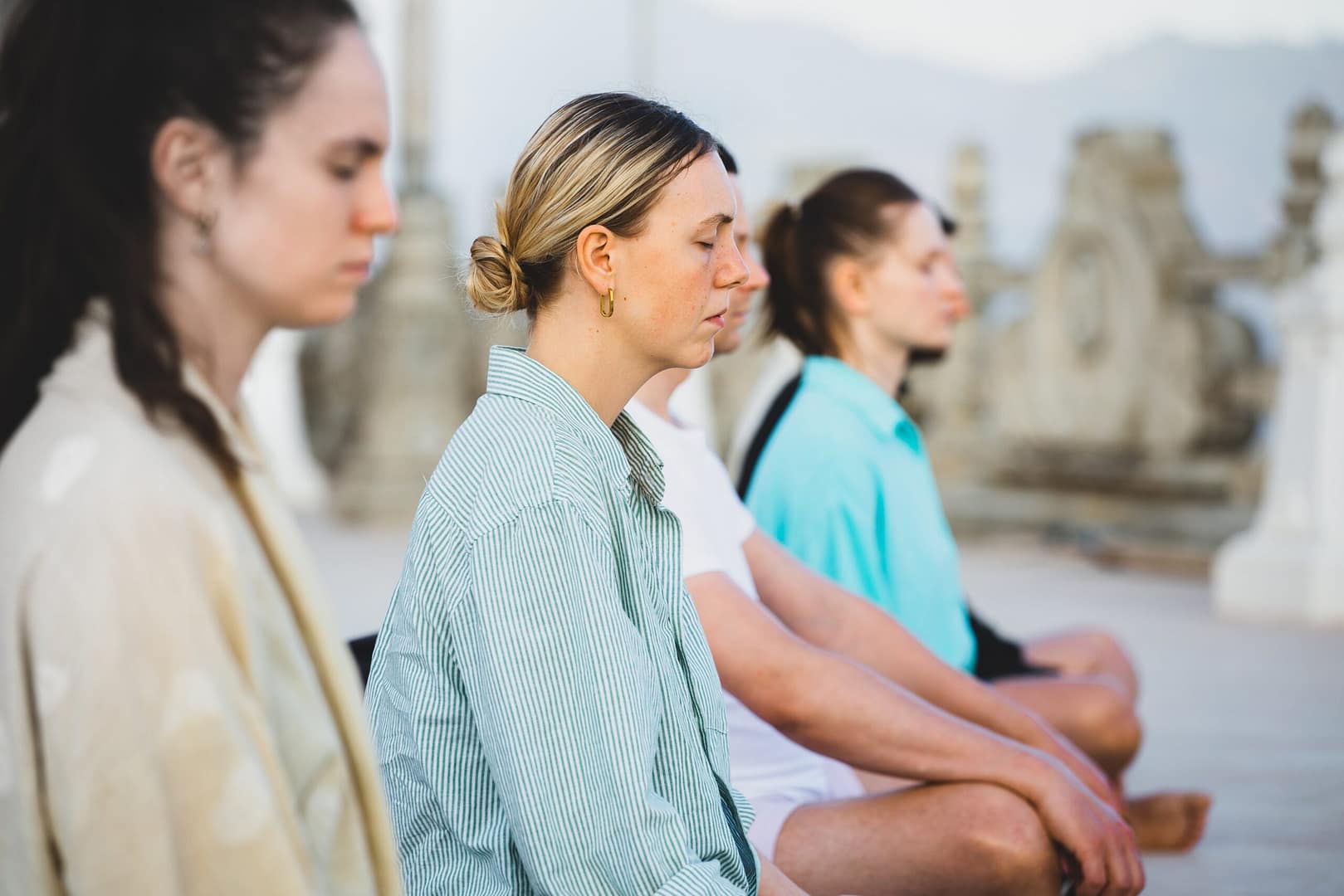 Grupo de mujeres de perfil practicando meditación en postura de loto, representando la sinergia grupal y el apoyo mutuo en la práctica de Mindfulness.